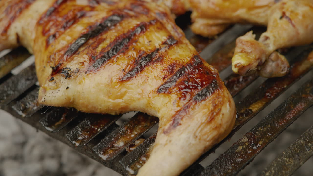 Primo piano di pezzi di pollo che grigliano sul barbecue.