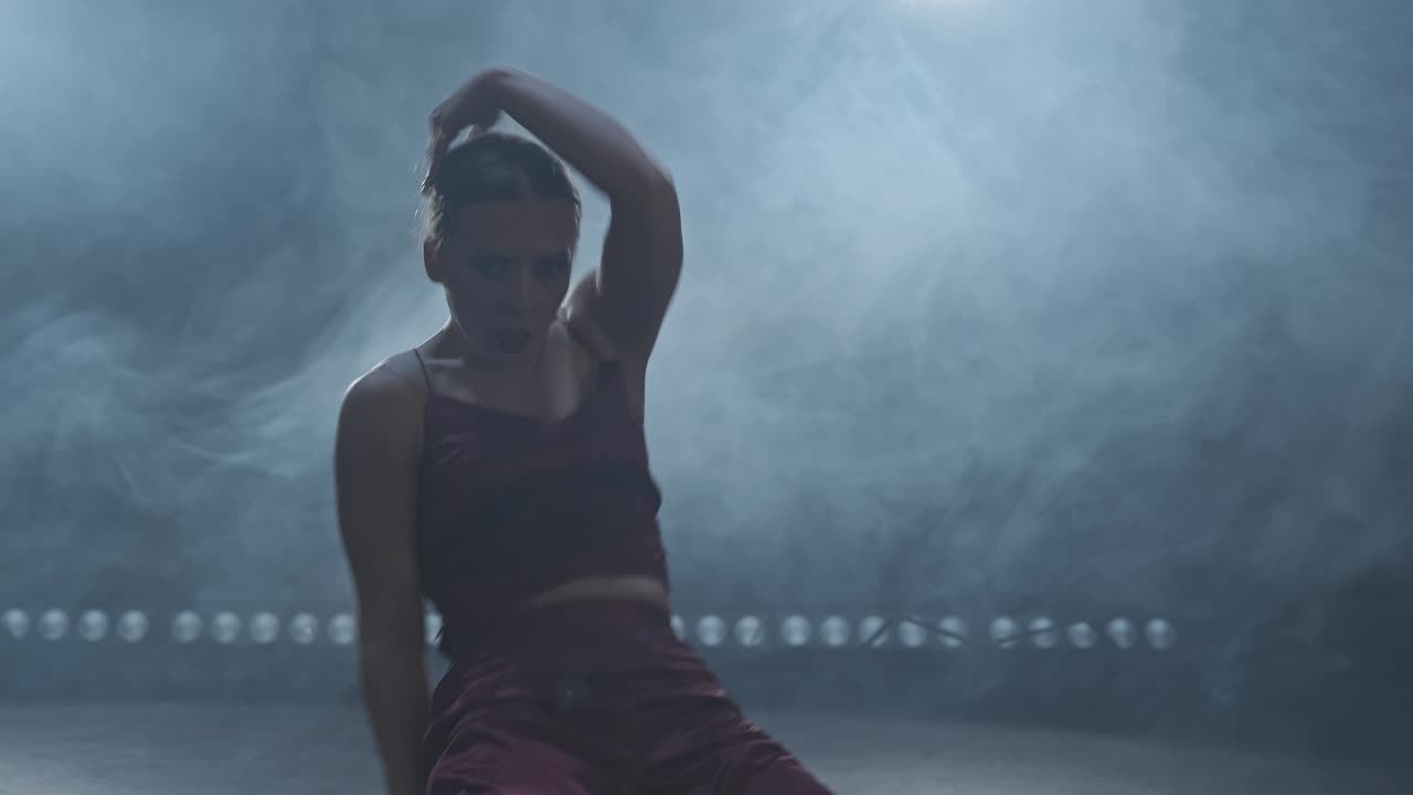 Elegant female dancing in studio with smoke and spotlight. Silhouette of woman