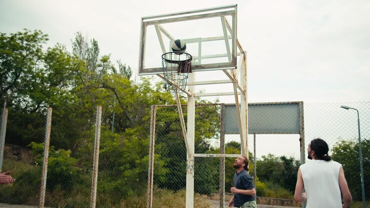 Dynamic basketball game on the street. A young man in a gray t-shirt scores a goal in a basketball hoop and is very happy about his success