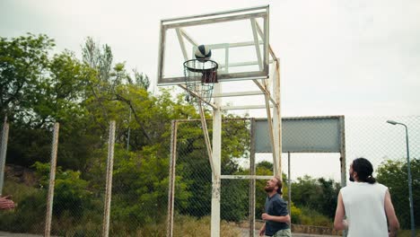 dynamic basketball game on the street. a young man in a gray t-shirt scores a goal in a basketball hoop and is very happy about his success