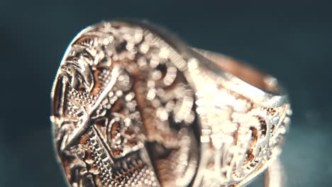 A-macro-detailed-tilt-down-shot-of-a-golden-textured-freemasons-ring,-on-a-rotating-stand,-mirror-reflection,-illuminati-symbol,-professional-studio-lighting,-4K-video