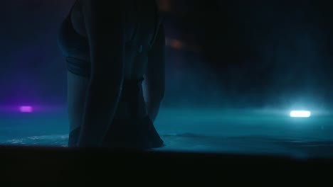 primer plano de una mujer entrando en la piscina por la noche