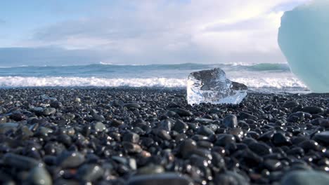 small piece of ice on pebbles, diamond beach in iceland with sea waves