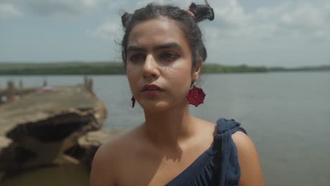 close up shot of an indian woman with a lost in thought near a river