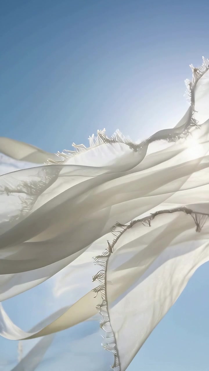 Video verticale: Pannelli bianchi che ondeggiano e si torcono nel cielo blu per il vento, orli sfilacciati retroilluminati dal sole, nastri.