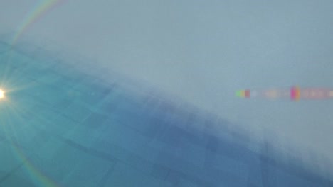 animación del destello de la lente del arco iris contra formas abstractas sobre fondo azul