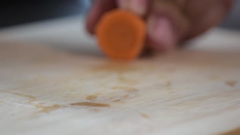 primer plano de la mano de una mujer cortando una zanahoria.
