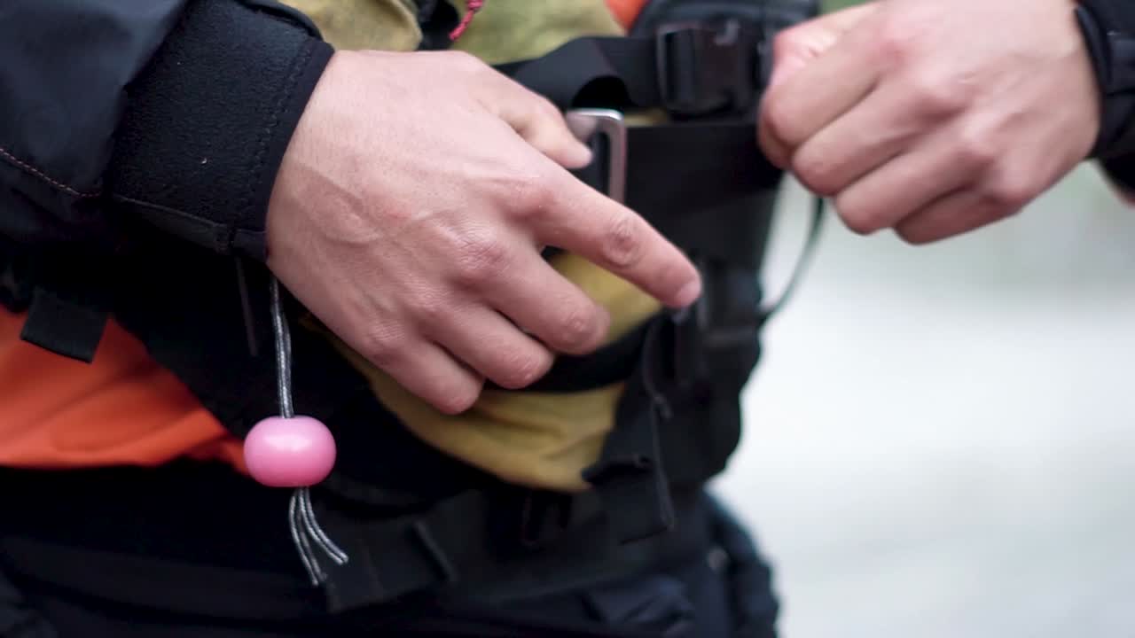 Caucasian man fastening safety suit with harness prior to adventure.