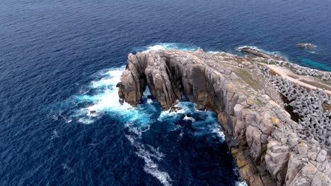 aerial drone shot of extreme waves crashing on the rugged paper cliff in costa da morte, morás, xove, lugo, galicia, spain on a cloudy day