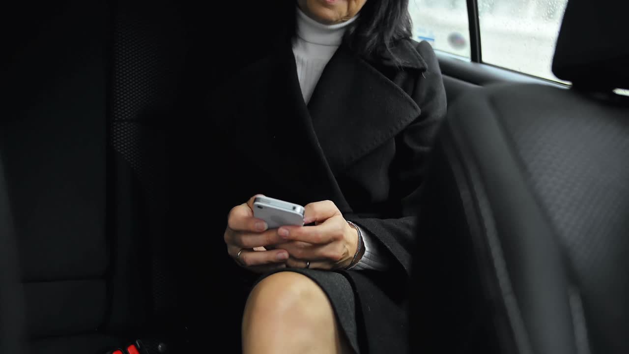 mujer de negocios sentada en el coche y usando el teléfono móvil