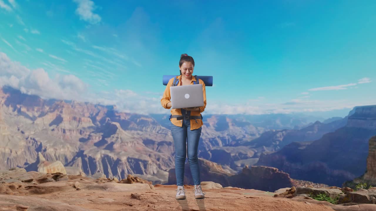 Full Body Of Asian Female Hiker With Mountaineering Backpack Using A Laptop While Traveling At The Top Of Mountain