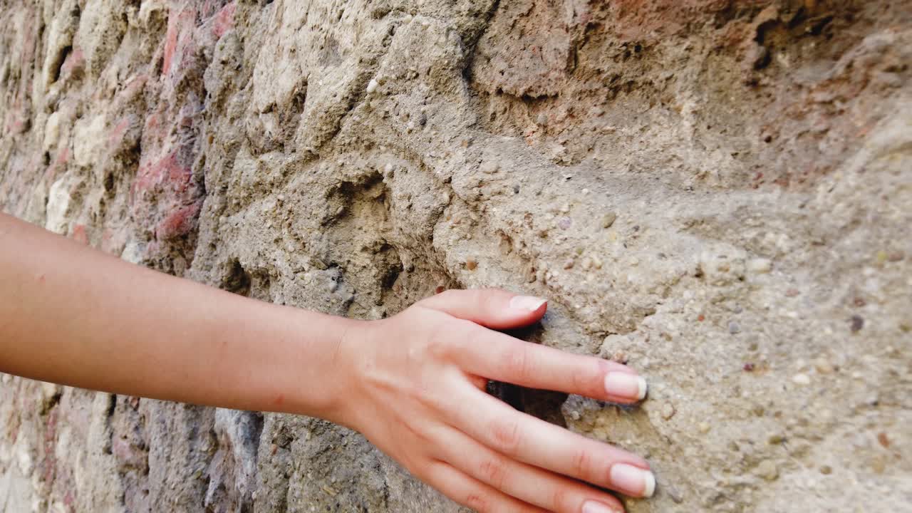 cámara súper lenta: hermosa joven toca la pared mientras camina por la calle
