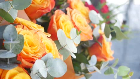 un ramo de rosas naranja y amarilla con eucalipto