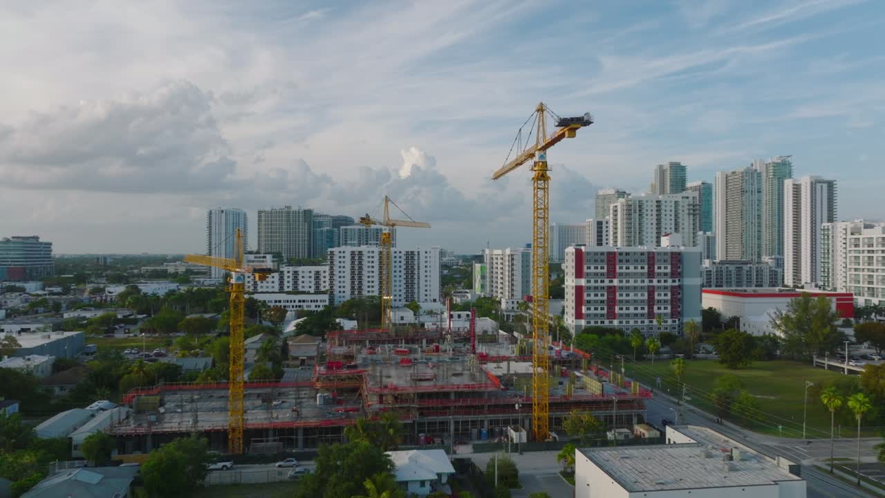 imágenes de diapositivas y panorámicas de grúas en el sitio de construcción al crepúsculo, desarrollo urbano en el fondo. miami, ee.uu.