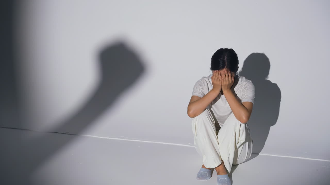 정신 건강 문제, 두통, 편두통, 정서적 불안 또는 공황 장애를 겪는 여성을 대상으로 한 가정 폭력으로 인해 얼굴을 손으로 가린 채 슬프게 울고 있는 스트레스 받고 우울한 젊은 여성.