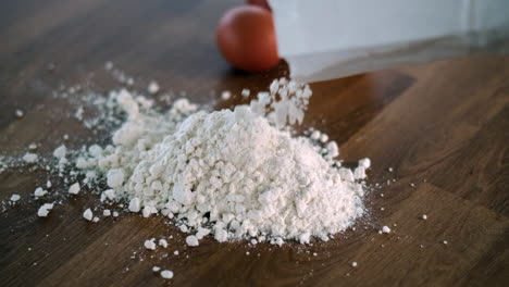 pouring flour on table for baking with eggs aside ready to mix