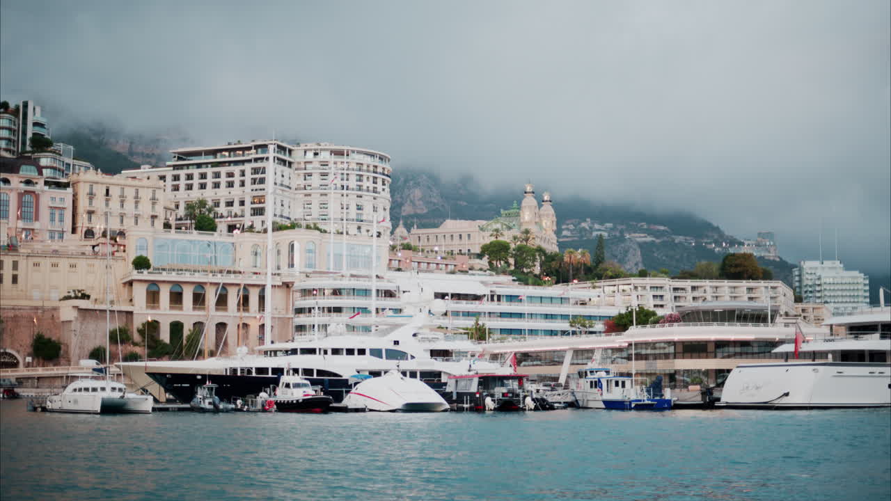 View of boats docked in the Monaco Marina with the skyline of the city on the background