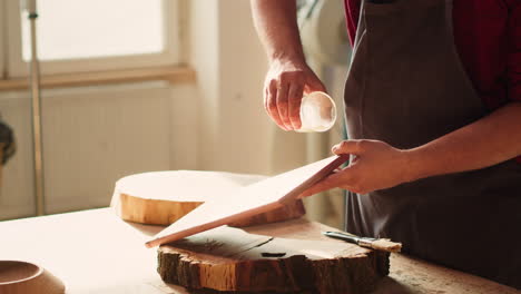 Cabinetmaker-in-assembly-shop-lacquering-wooden-board,-close-up