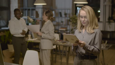 blonde businesswoman using tablet while standing in the office