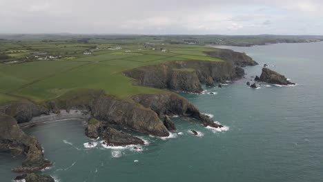 Drone-shot-of-a-coastline-in-rural-Ireland-with-many-sea-cliffs,-beaches-and-rock-formations-on-a-cloudy-day