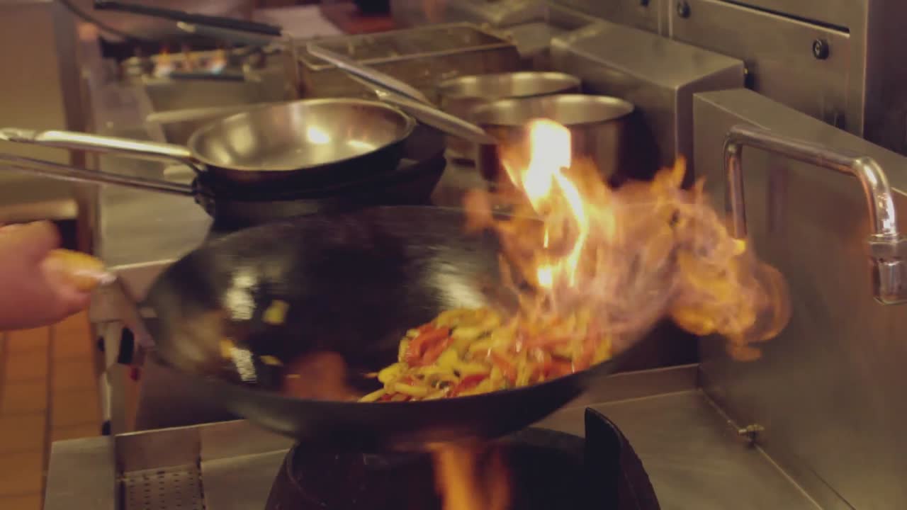 Chef che fa saltare in padella un piatto fiammeggiante