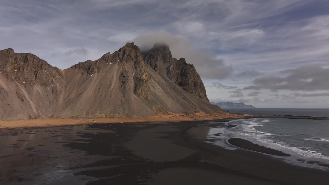 Vestrahorn and black sand beach at Stokksnes, Iceland drone view, coastal cliffs meet arctic surf view.