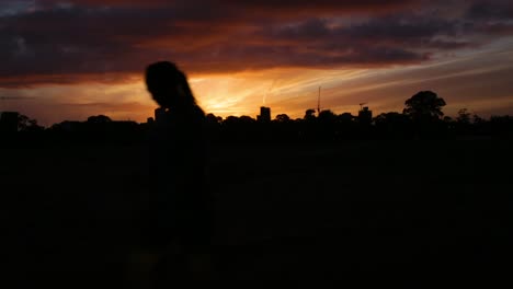 a vibrant sunset from behind the silhouette of a cityscape