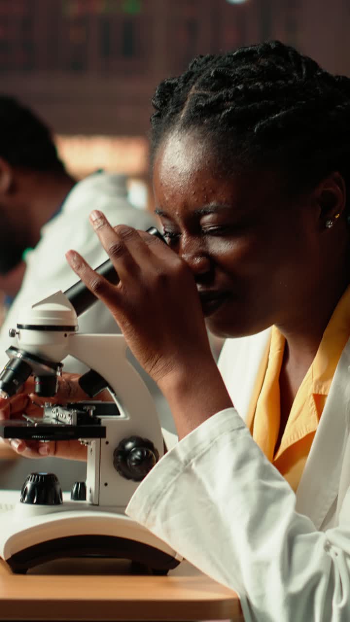 Scienziata afroamericana che usa un microscopio in laboratorio