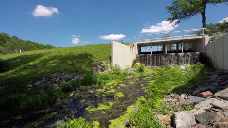 reservoir barrier near a watermill with a creek and boulders with moss, sunny