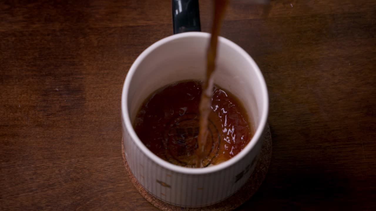 Super slow motion of hot delicious coffee being poured into an elegant mug