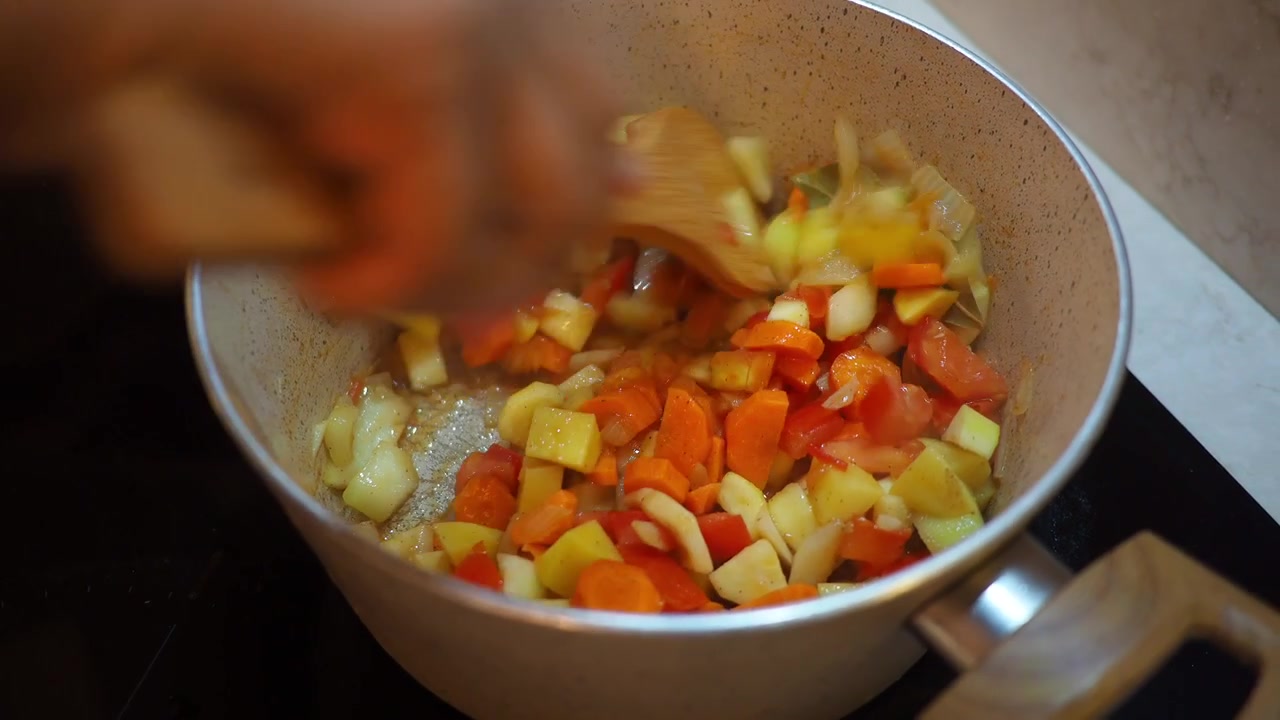Frisches gewürfeltes Gemüse in einem Topf mit einem Holzlöffel kochen