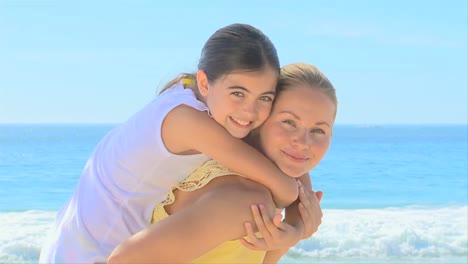 mujer dando a su hija un cochecito en la playa