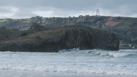 hermosas imágenes en cámara lenta de olas rompiendo en el océano con la costa rocosa en el fondo