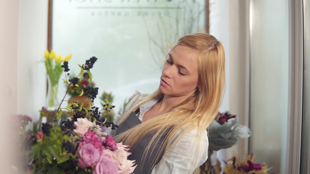 Professional blonde female floral artist arranging beautiful wedding bouquet at flower shot. Floristry, handmade and small