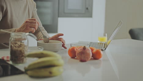 person eating breakfast and working on laptop