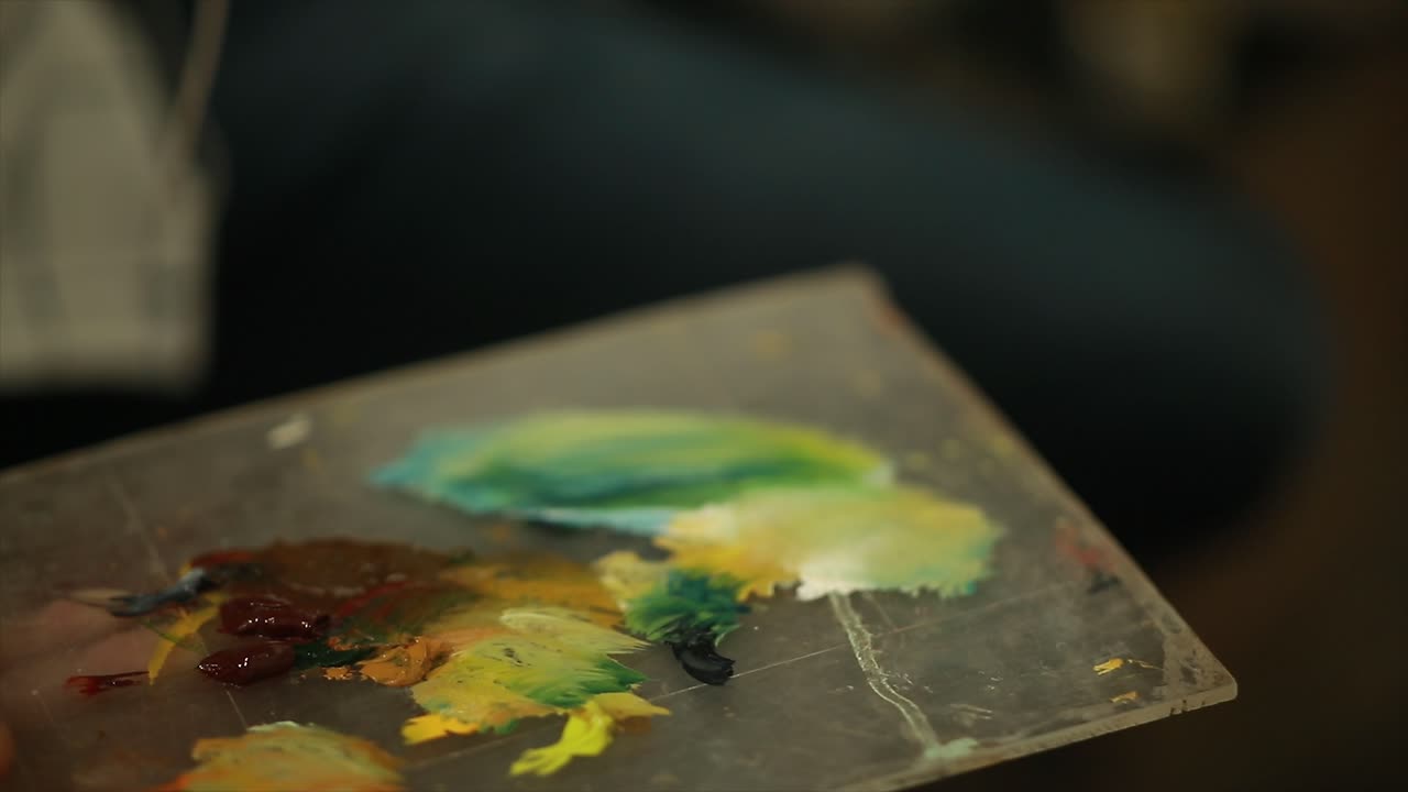 pintor de arte feliz sosteniendo paleta de artista y pintando sobre lienzo