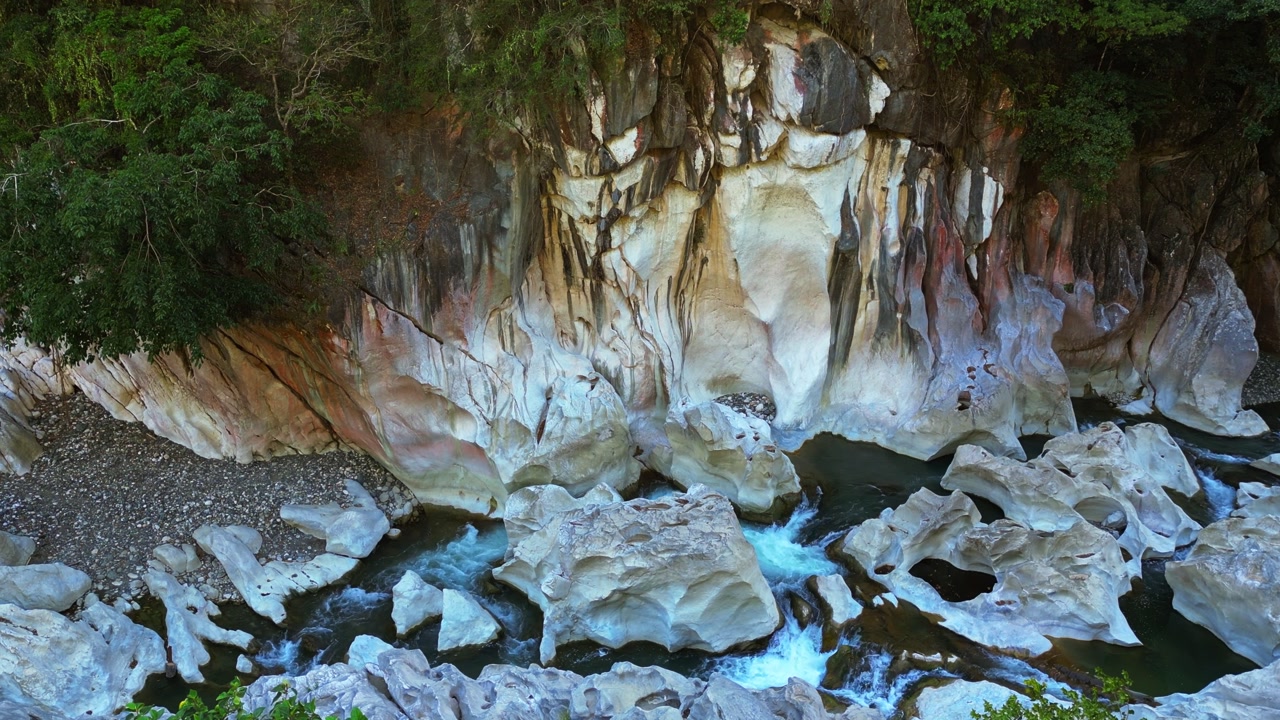 A sweeping side-view shot frames the riverside rock formations and surrounding nature, emphasizing texture and beauty at Tinipak River, Tanay, Rizal.