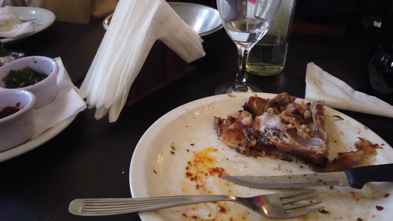 Close-up de prato vazio após refeição de frango e carne em um restaurante de asado sul-americano.