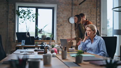 serious entrepreneur talking smartphone looking laptop screen at workplace.