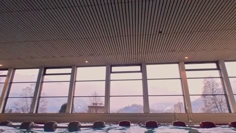 a water level shot following a man swimming in an indoor pool in the mountains of switzerland