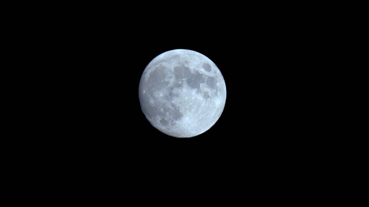 Detalhe em close-up de lua cheia iluminada em um céu noturno escuro.