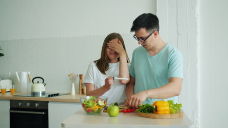 couple reacts to pregnancy test results in the kitchen while preparing a salad