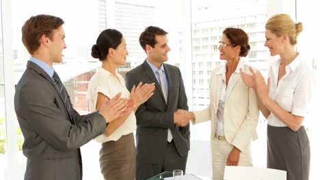 Business-people-shaking-hands-at-interview-while-others-clap