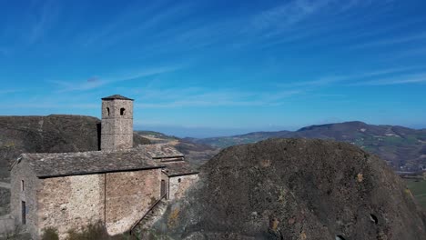 imágenes aéreas de pietra perduca, roca volcánica, iglesia situada en la piedra superior inmersa en el paisaje rural, tierra cultivada en val trebbia bobbio, emilia romagna, italia