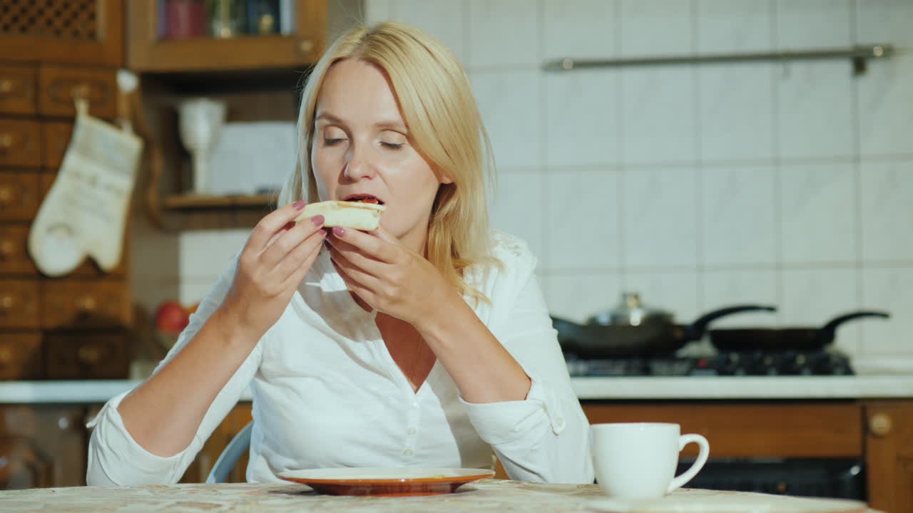 una joven come pizza en su cocina video 4k