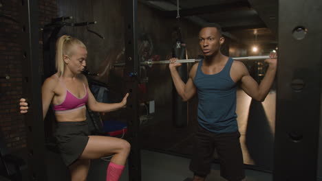 caucasian female monitor and an athletic african american man in the gym.