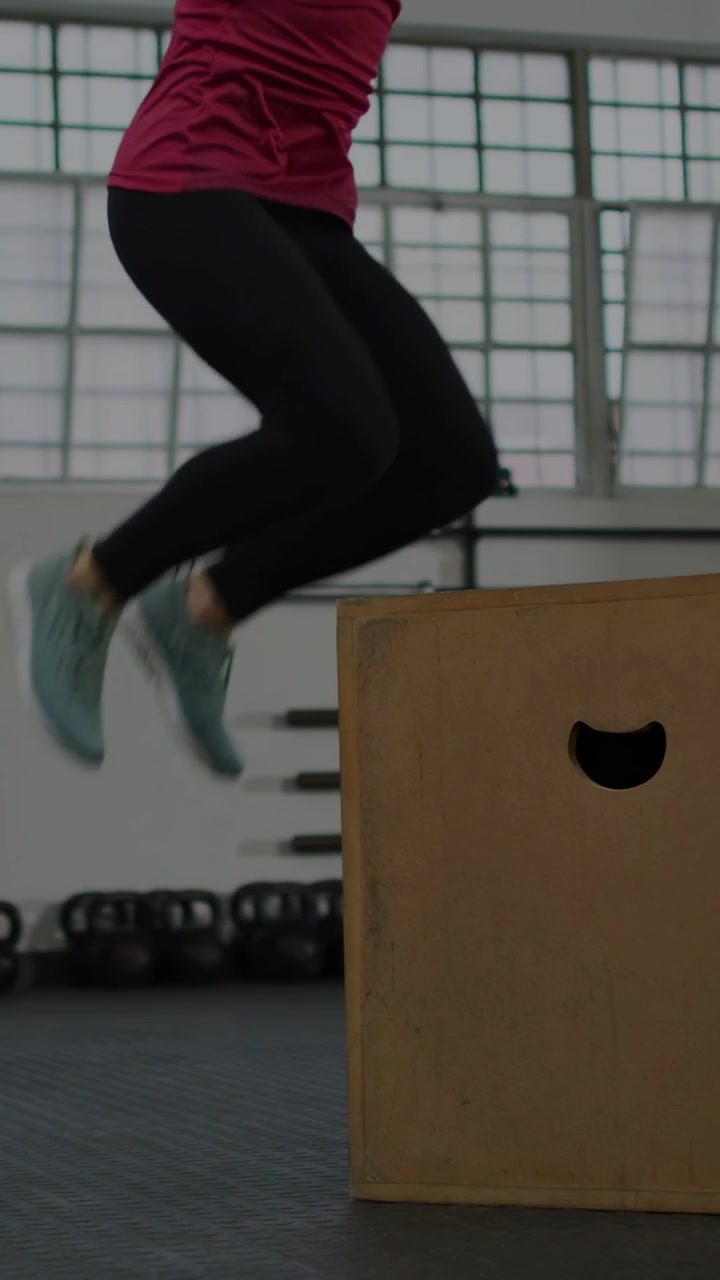 Video verticale: Donna che fa uno squat, salta su una plyo box, atterra, scende, con barre grafiche sovrapposte alla palestra.