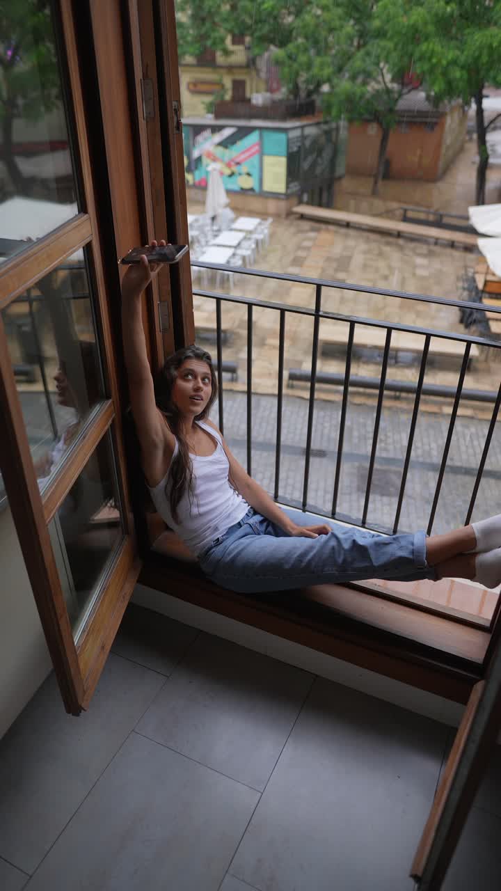 mujer tomando una selfie en un balcón en un día de lluvia