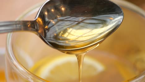 honey dripping into a glass of lemon tea