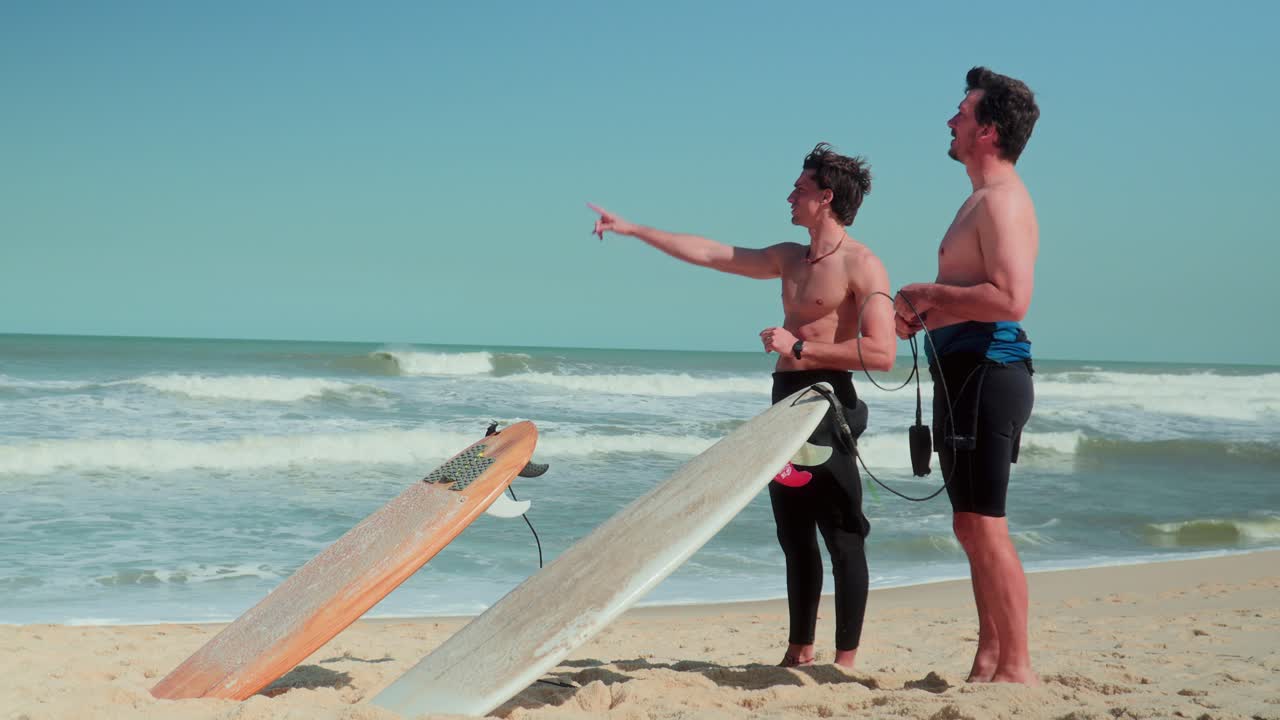 Two surfers on a sunny beach preparing to enter the water